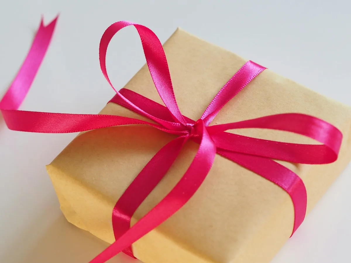 Kleines Geschenk in Kraftpapier mit pinker Schleife